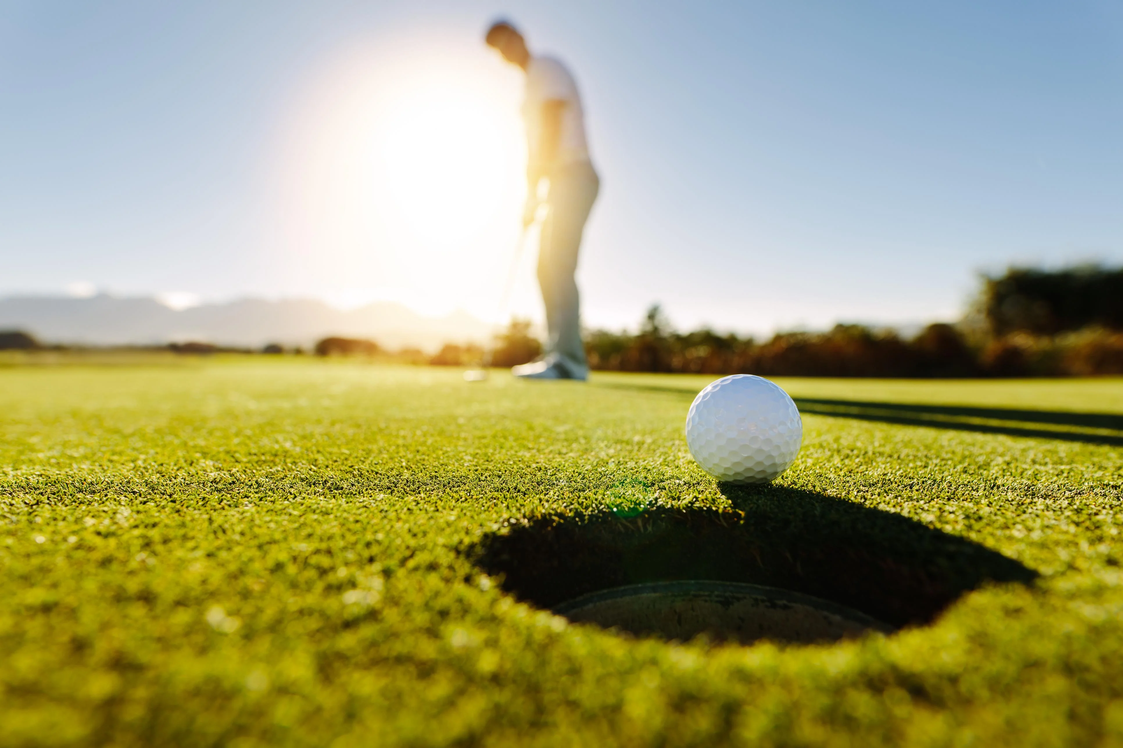 blurred image of golfer putting the ball on the fairways